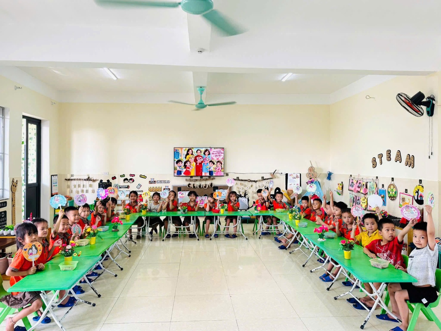 'A group of children sitting at tables in a classroom
Description automatically generated'