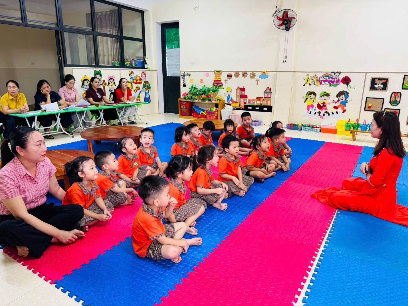'A group of children sitting on a mat in a classroom
Description automatically generated'